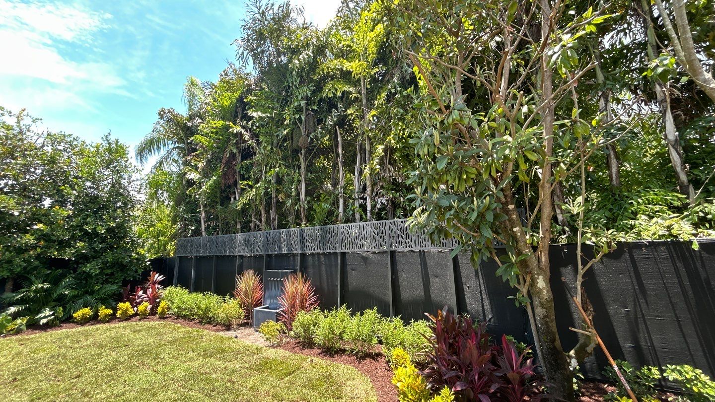 Layered tropical planting along a modern privacy wall